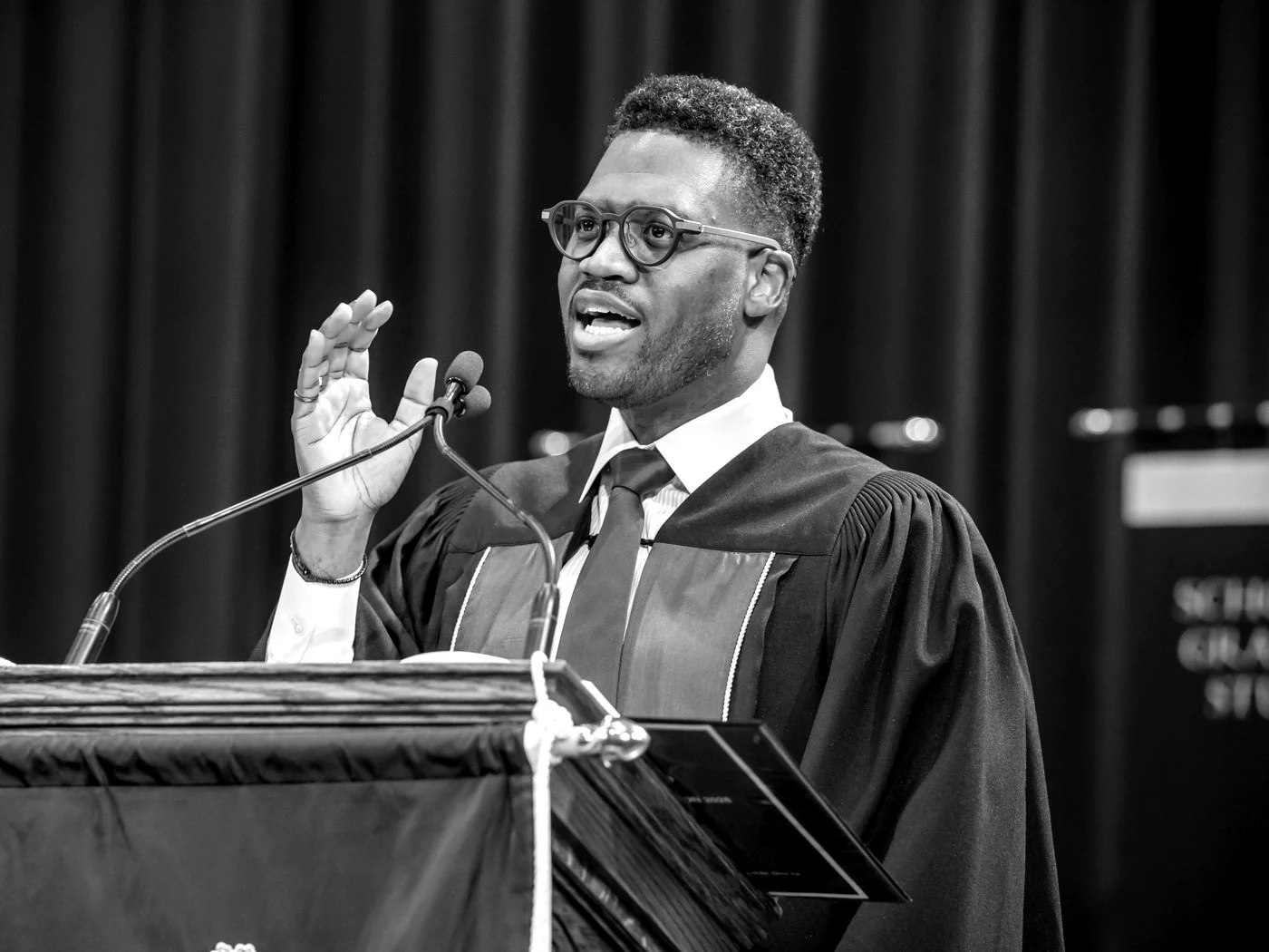 Andrew Forde speaking at a lectern in academic robes